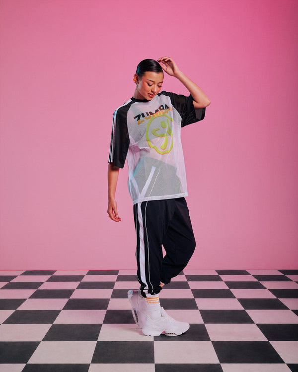 Female model wearing a white mesh raglan tee with black and white striped sleeves, a big yellow and orange Zumbito logo and 