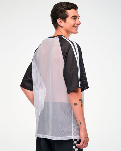 Shown from the back, male model wearing a white mesh oversized tee with black and white striped sleeves, paired with black and white checkerboard pants.