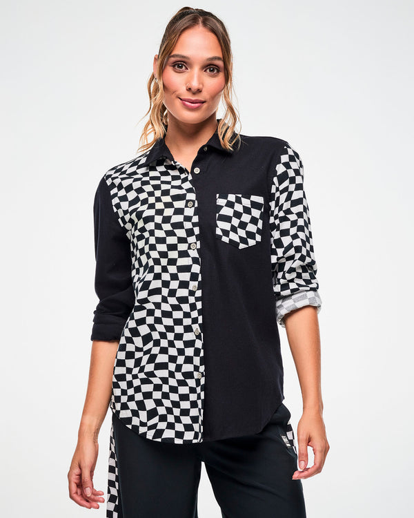 Female model wearing a black and white checkered flannel button-up with rolled sleeves, paired with black pants.