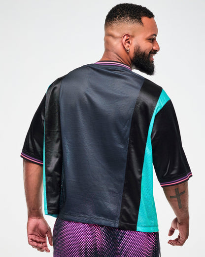 Shown from the back, male model wearing an oversized black jersey tee with an aqua side panel.