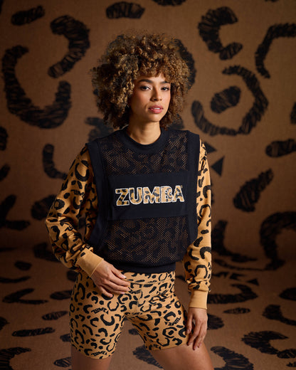 Black mesh Zumba top on female model with a leopard print sweatshirt underneath with biker shorts against a tan leopard backdrop.