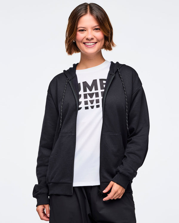 Front view of a female model wearing an open black zip-up hoodie, layered over a white 