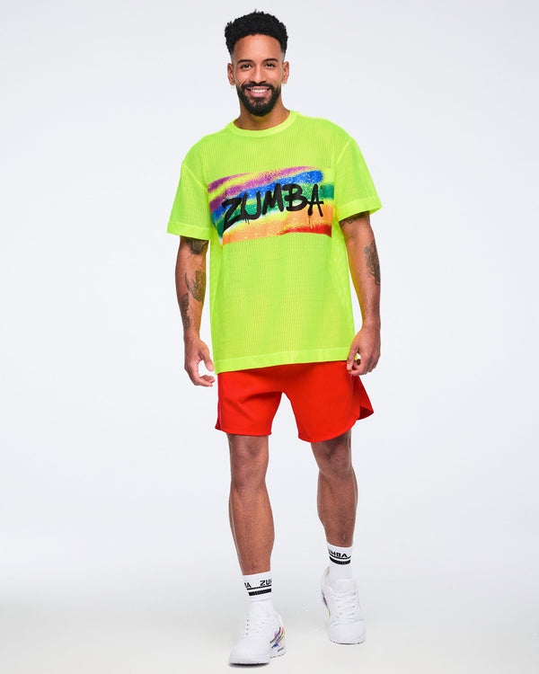 Male model wearing a bright yellow Zumba t-shirt and red shorts on a white background.