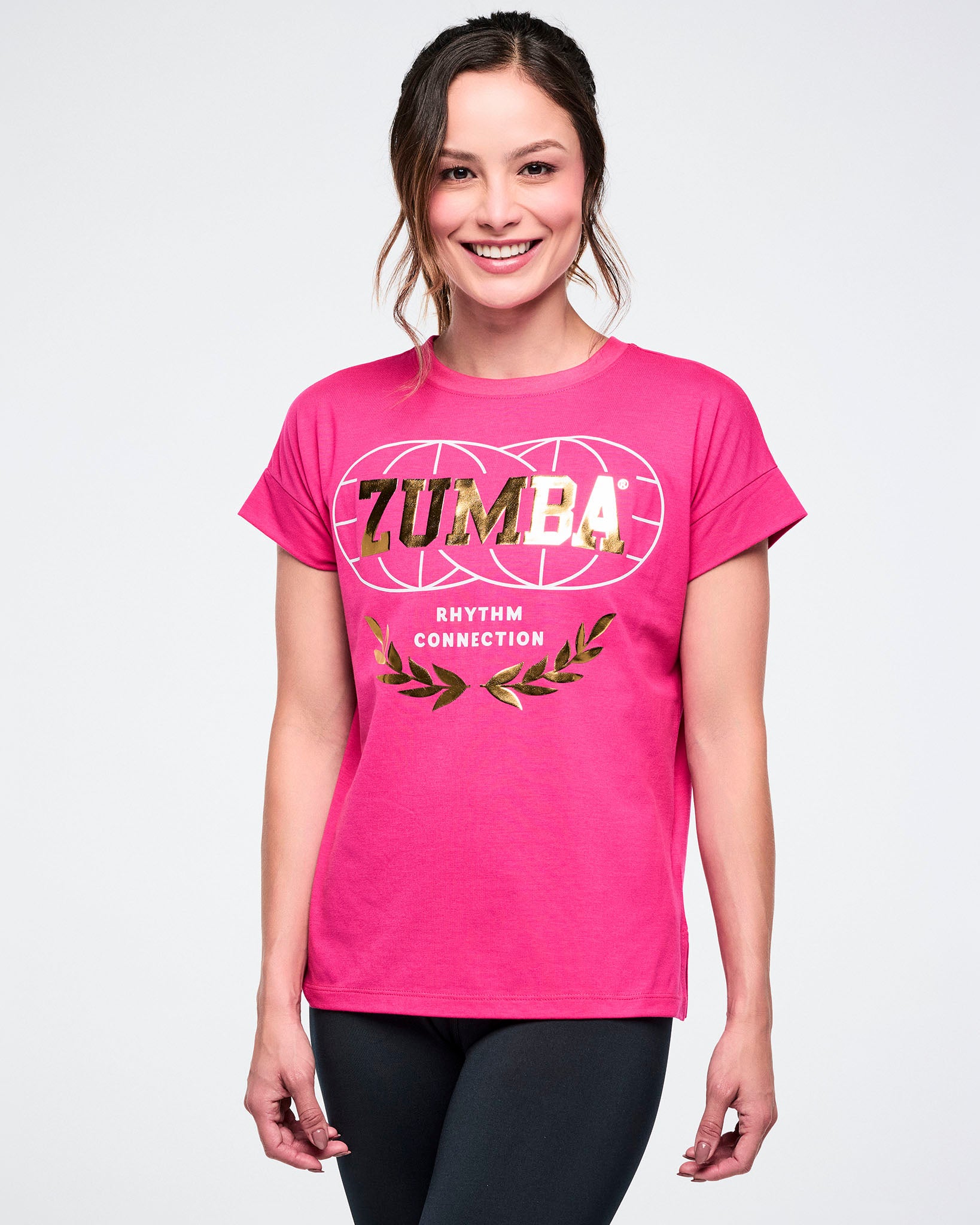 Female model wearing a pink Zumba t-shirt on a white background.