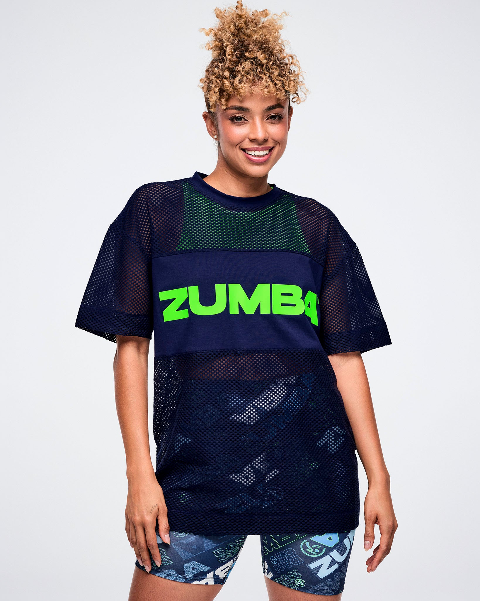 Female model wearing an indigo Zumba branded mesh top.