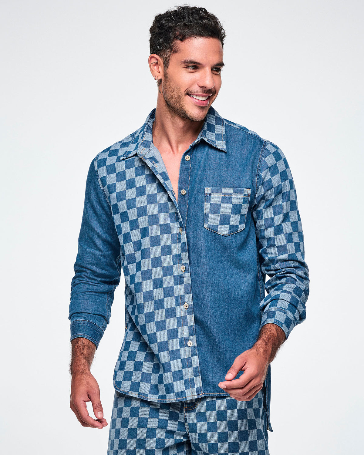 Close-up front view of a male model wearing a denim button-down with a checkerboard front panel, chest pocket, and left sleeve.