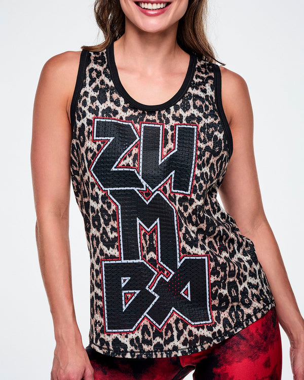 Close-up of a female model wearing a basketball tank top with a black, beige, and white leopard print pattern, featuring large vertical 'ZUMBA' rock-like text in black with red and white outlines, paired with red and black leggings.