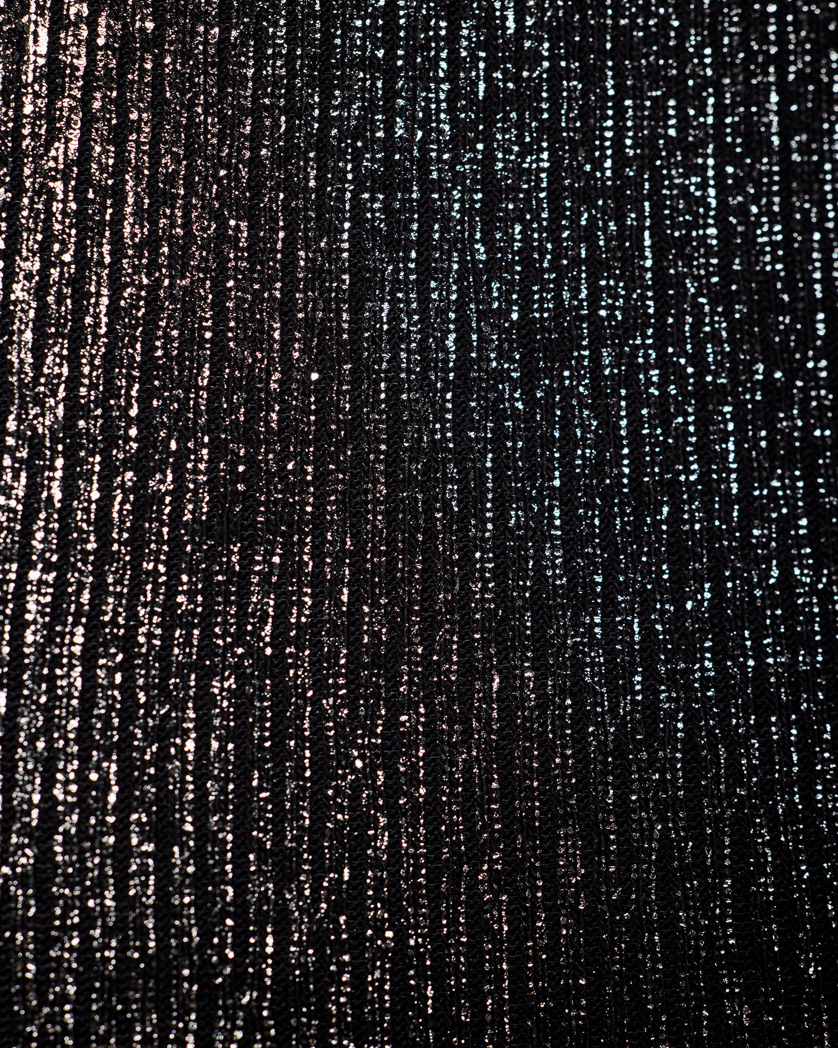 A close-up of a textured black fabric with vertical metallic silver and bronze shimmering streaks.