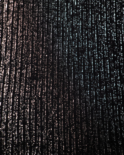 A close-up of a textured black fabric with vertical metallic silver and bronze shimmering streaks.