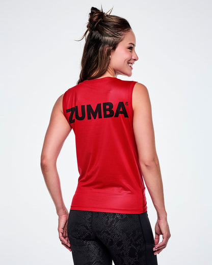 A female model shown from the back, wearing a red sleeveless athletic top with the brand name 'ZUMBA' printed in black across the upper back, paired with black leggings.