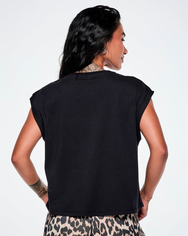 A female model shown from the back wearing a black sleeveless tank paired with leopard print leggings.