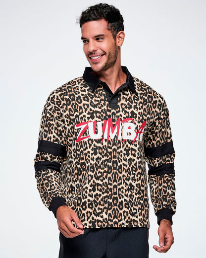 A male model wearing a long-sleeve leopard-print polo shirt with black collar, cuffs, and sleeve stripes, featuring red and white 'ZUMBA' text across the chest, paired with black pants against a white background.
