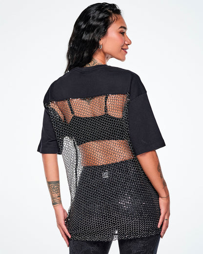 A female model shown from the back wearing a black tee, with a larger mesh and chain-link sheer mesh panel with sequins covering most of her back, paired with black leggings.