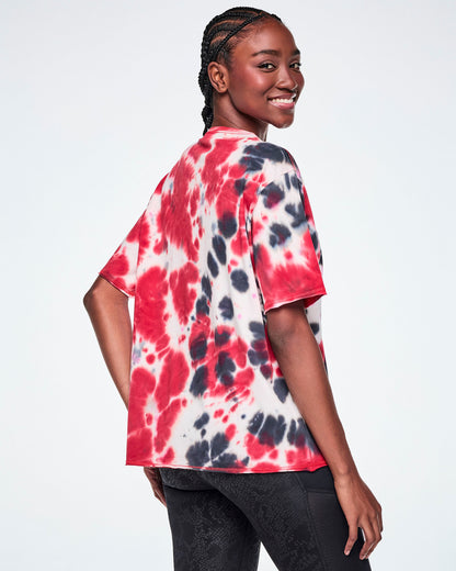 Back view of a female model wearing an oversized red, white, and black tie-dye patterned tee, paired with black leggings.