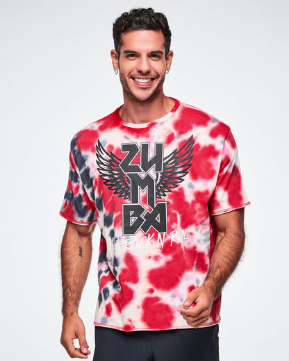 A male model wearing an oversized red, white, and black tie-dye patterned tee with a large black winged 'ZUMBA' rock / metal like logo and white 'LOVE+ROCK N' ROLL," paired with black pants.