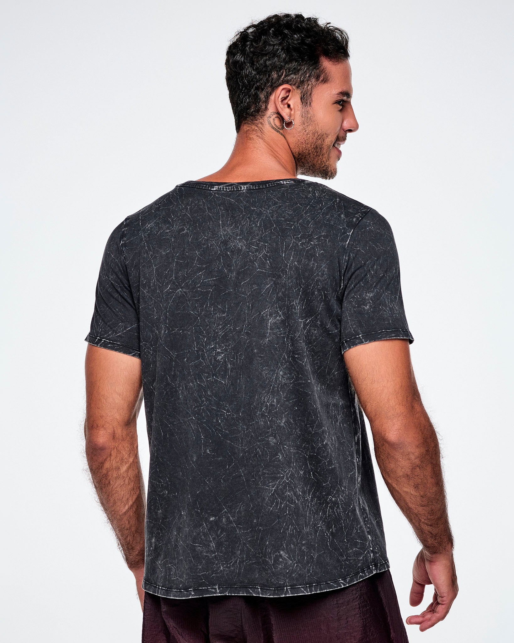 Back view of a male model wearing a black acid-washed patterned Zumba graphic tee, paired with gradient red and black pants.