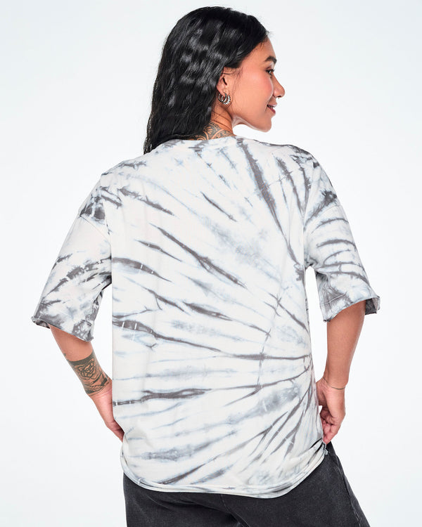 Back view of a female model wearing a white and gray tie-dye patterned graphic tee, paired with black pants.