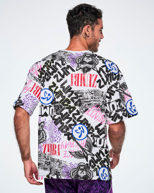 Back view of a male model wearing a graphic tee with black, white, pink, and blue graffiti-style print and logos, such as blue zumbitos, a tiger wearing sunglasses, 