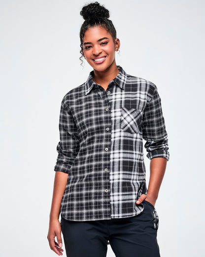 A female model wearing a black and white plaid button-down shirt with rolled-up sleeves and dark pants.