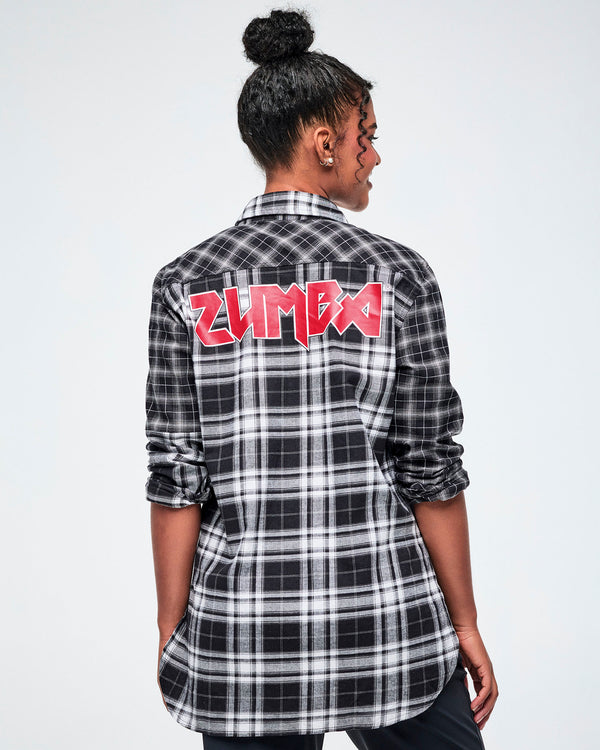 A female model shown from the back, wearing a black and white plaid button-down shirt with a red rock-like 'ZUMBA' text across the upper back, set against a white background. 