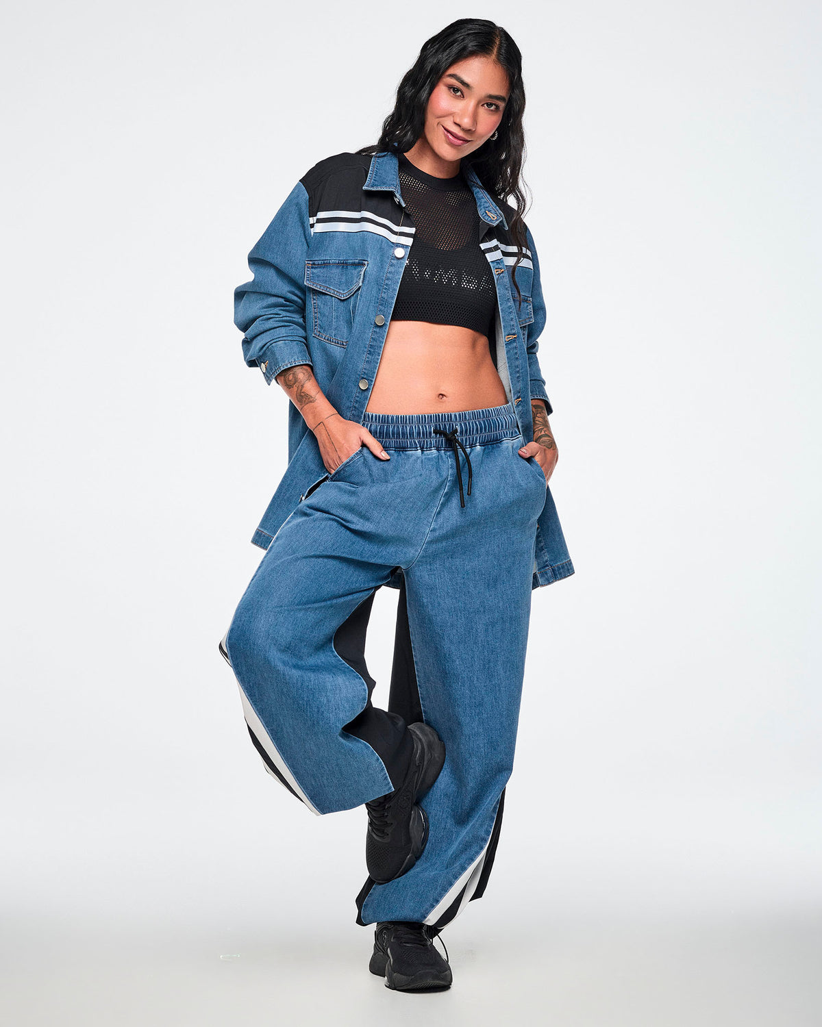 Female model wearing a black double-layer mesh Dale-Z crop bra under a denim shacket, paired with wide-leg denim pants and black sneakers.