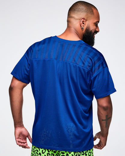 Back view of a male model wearing a blue mesh jersey with green leopard pants.