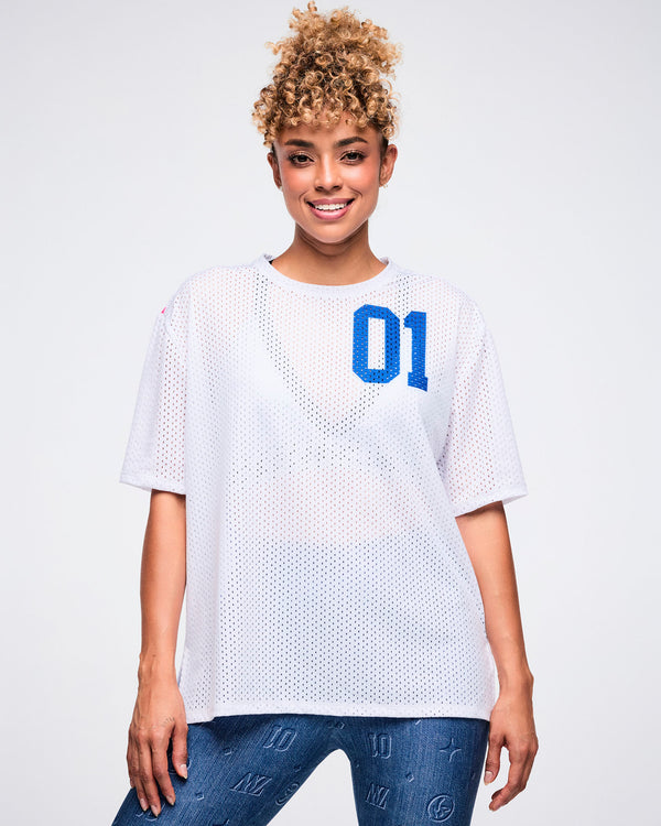 Female model in a white mesh top with blue “01” on the upper left, paired with blue denim leggings.