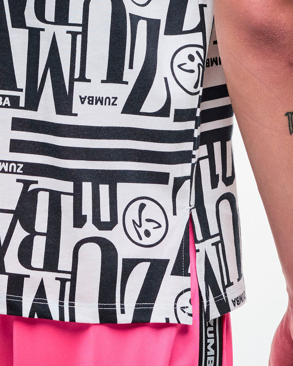 Close-up of a male model in a black-and-white patterned Zumba boxy top, highlighting the side slits, paired with pink pants.