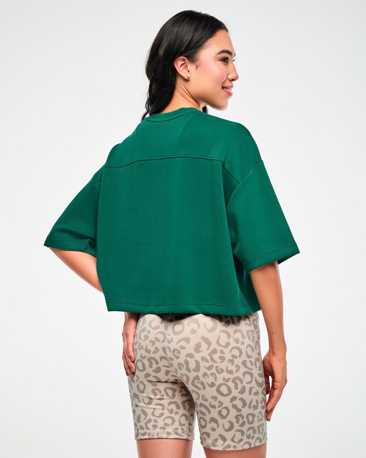 Back view of a female model in the teal green drop shoulder crop top, showing the back yoke seam, wide elbow-length sleeves, and boxy cropped hem.