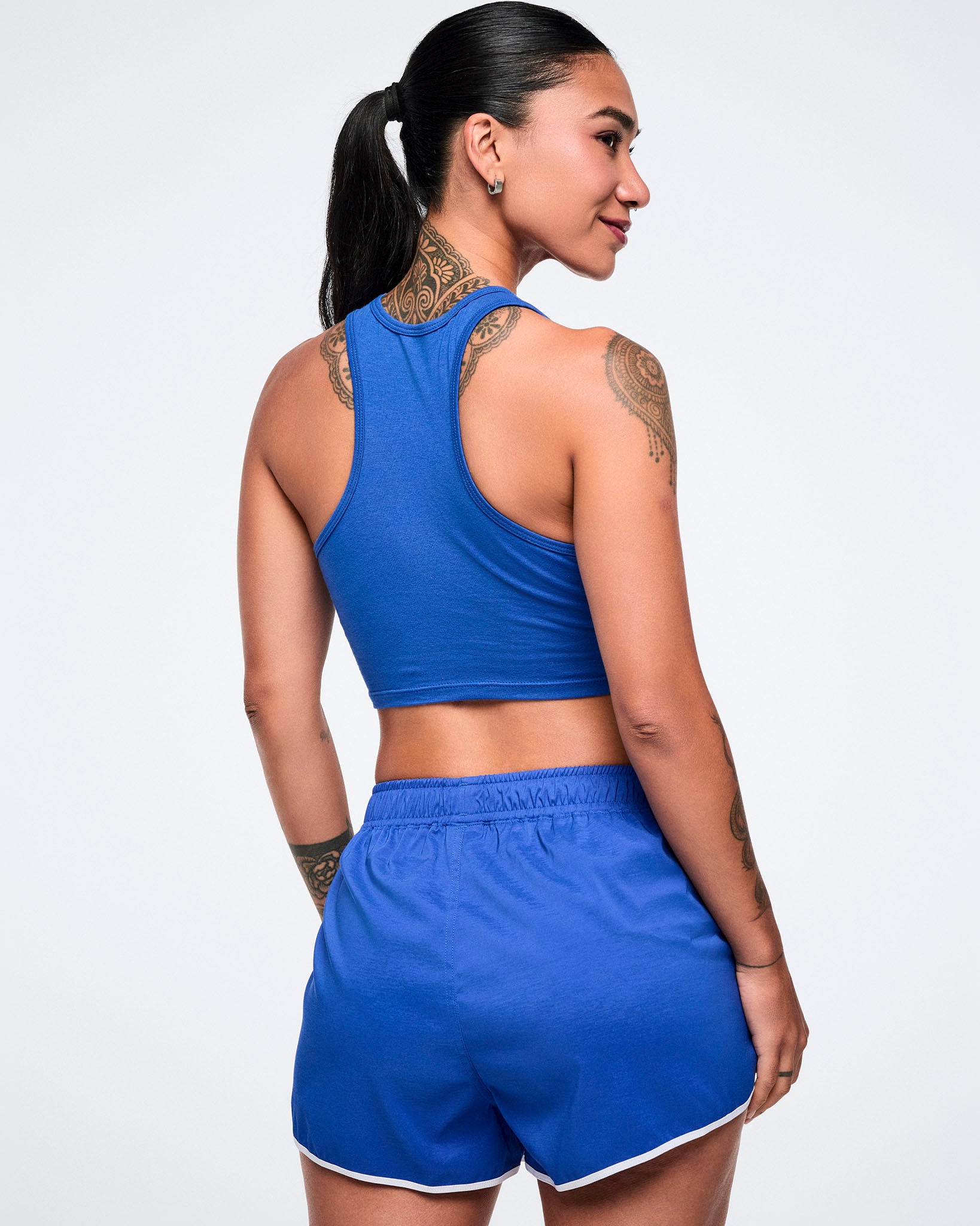Back view of a female model wearing a blue crop racerback and matching shorts.