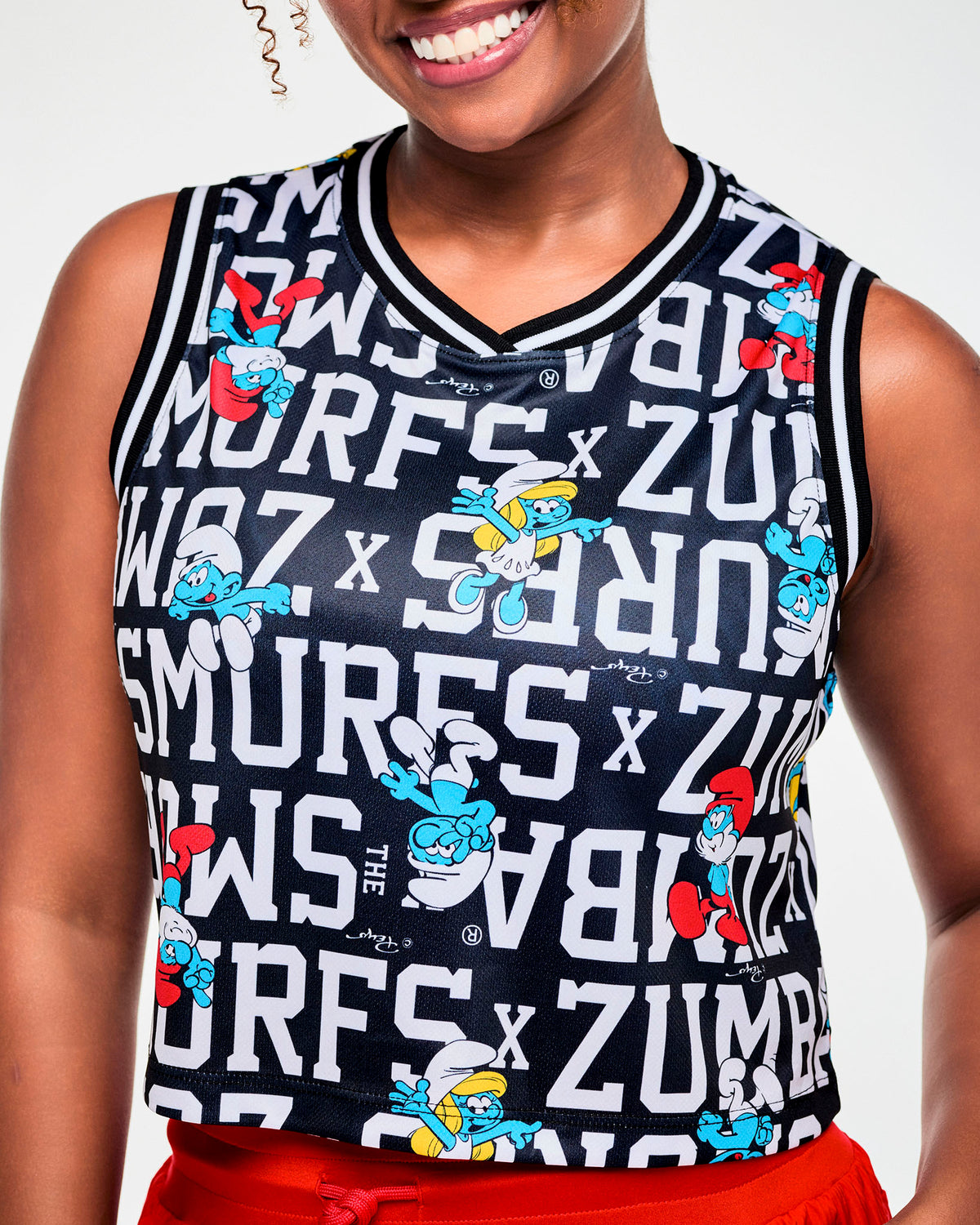 Close-up of the crop tank's print, showing Smurfette, Papa Smurf, and a smiling Smurf among the white block letters, plus the striped crossover V-neck trim.