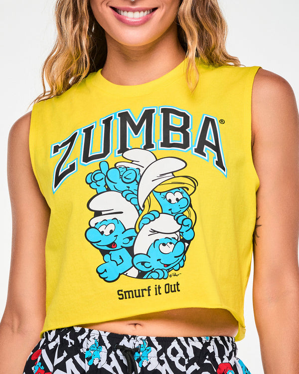 Close-up of the yellow crop tank's front graphic: arched black varsity 'ZUMBA' text outlined in blue over four Smurfs, including Brainy and Smurfette, huddled together, with black 'Smurf it Out' text below.