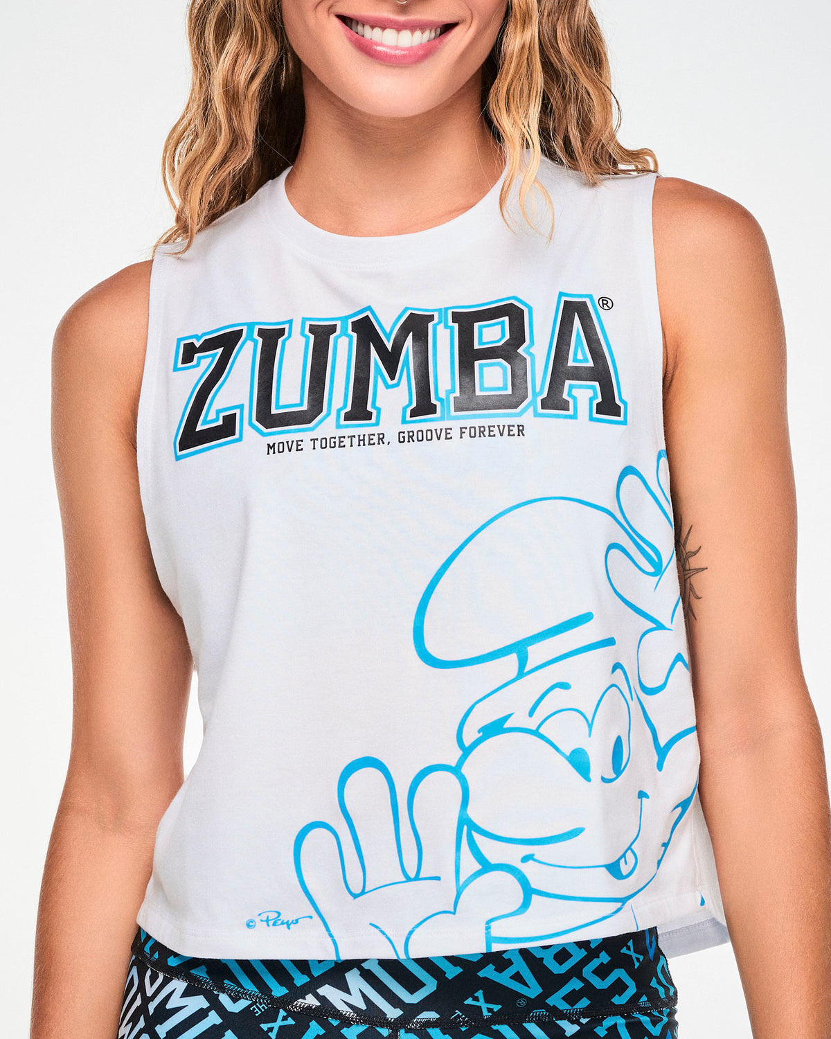 Close-up of the white tank's graphic: black varsity 'ZUMBA' text outlined in blue above 'MOVE TOGETHER, GROOVE FOREVER,' with a large blue line drawing of a Smurf waving near the hem.