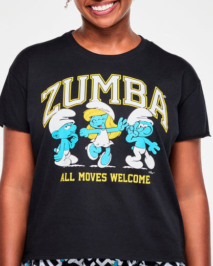 Close-up of the black top's graphic: white varsity 'ZUMBA' text outlined in yellow arched over three dancing Smurfs, including Smurfette, with yellow 'ALL MOVES WELCOME' text below.