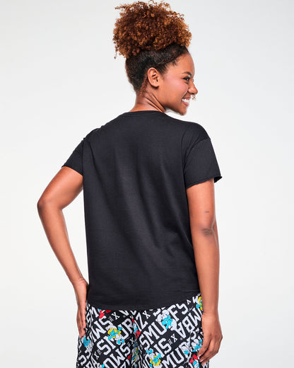 Back view of a female model in the black Smurfs graphic top, showing a plain back and the rounded hem that dips longer in the back.