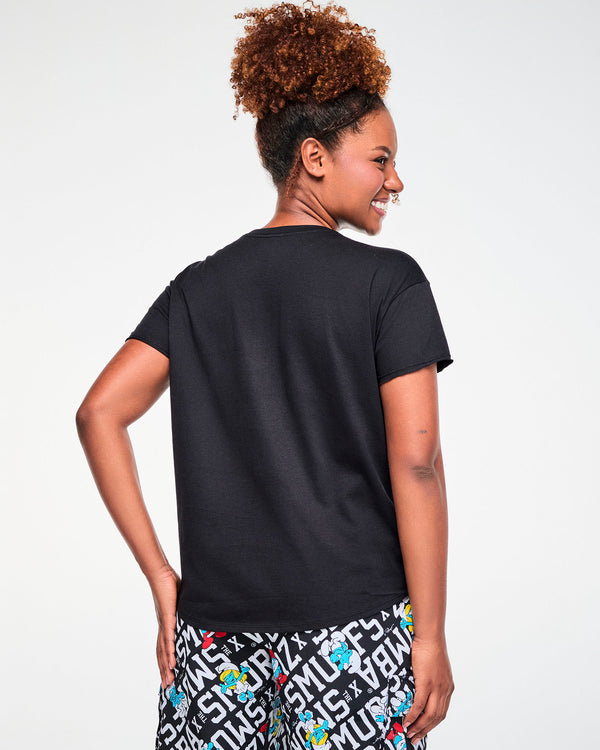 Back view of a female model in the black Smurfs graphic top, showing a plain back and the rounded hem that dips longer in the back.