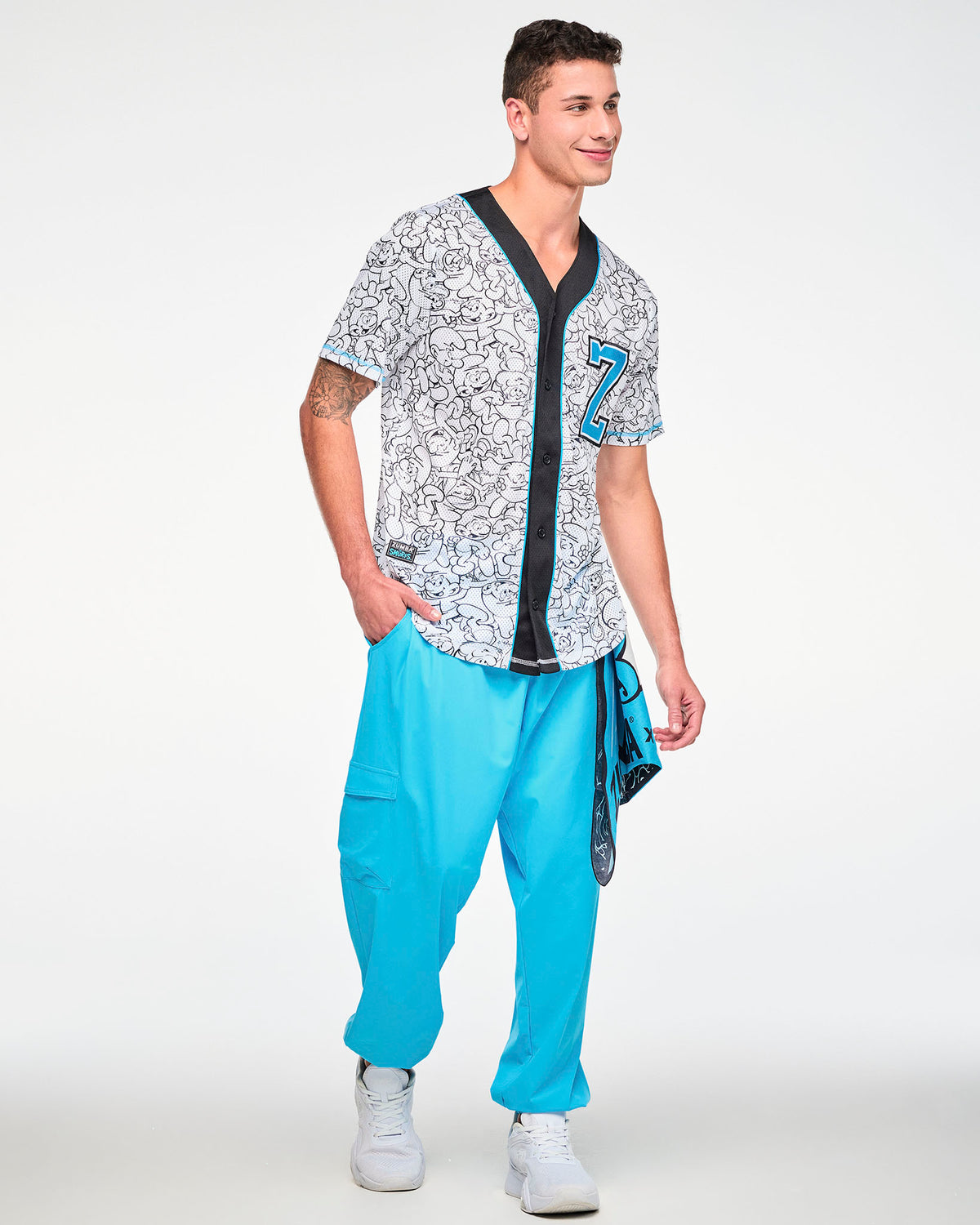 Male model in the Smurfs line-art baseball jersey, buttoned up with the light blue 'Z' on the chest, paired with aqua blue cargo pants and a bandana hanging at the hip.