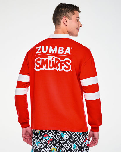 Shown from the back, a male model in the red rugby polo, with the embroidered 'ZUMBA' and 'THE SMURFS' logos across the shoulders and ribbed cuffs at the wrists.