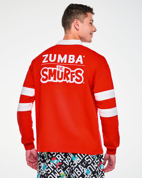 Shown from the back, a male model in the red rugby polo, with the embroidered 'ZUMBA' and 'THE SMURFS' logos across the shoulders and ribbed cuffs at the wrists.