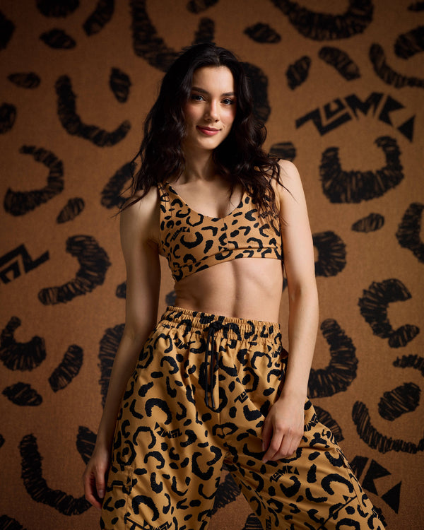 Leopard print bra top and cargo pants on female model against a tan leopard print backdrop.
