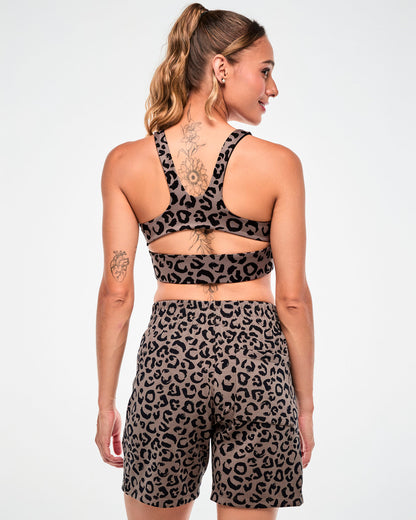 Back view of a female model in the brown leopard print racerback bra with a keyhole cutout, paired with matching leopard print shorts.