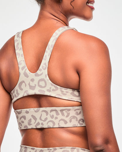 Close-up back view of the beige leopard print bra, showing the racerback straps and keyhole cutout above the wide underband.