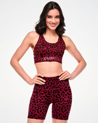 Female model with hands on her hips in the dark red leopard print longline bra and matching high-waisted biker shorts.