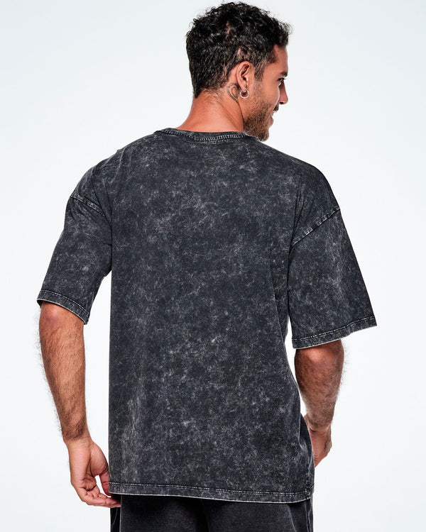 Back view of a male model wearing a black acid-wash graphic tee, paired with red and black leggings.