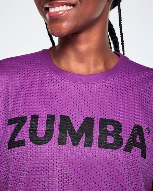 Close-up of a female model wearing a purple Zumba mesh top with a black ZUMBA lettering across the chest.