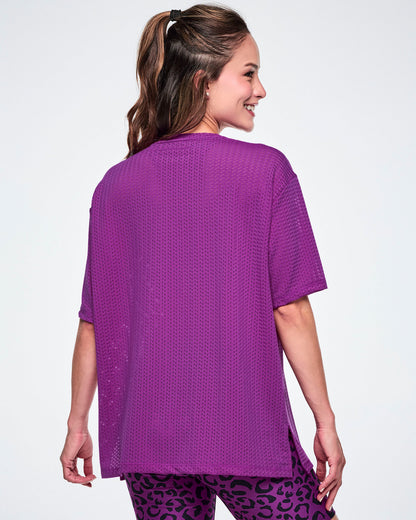 Back view of a female model in a purple oversized mesh boxy top, paired with purple leopard-print biker shorts against a white background.