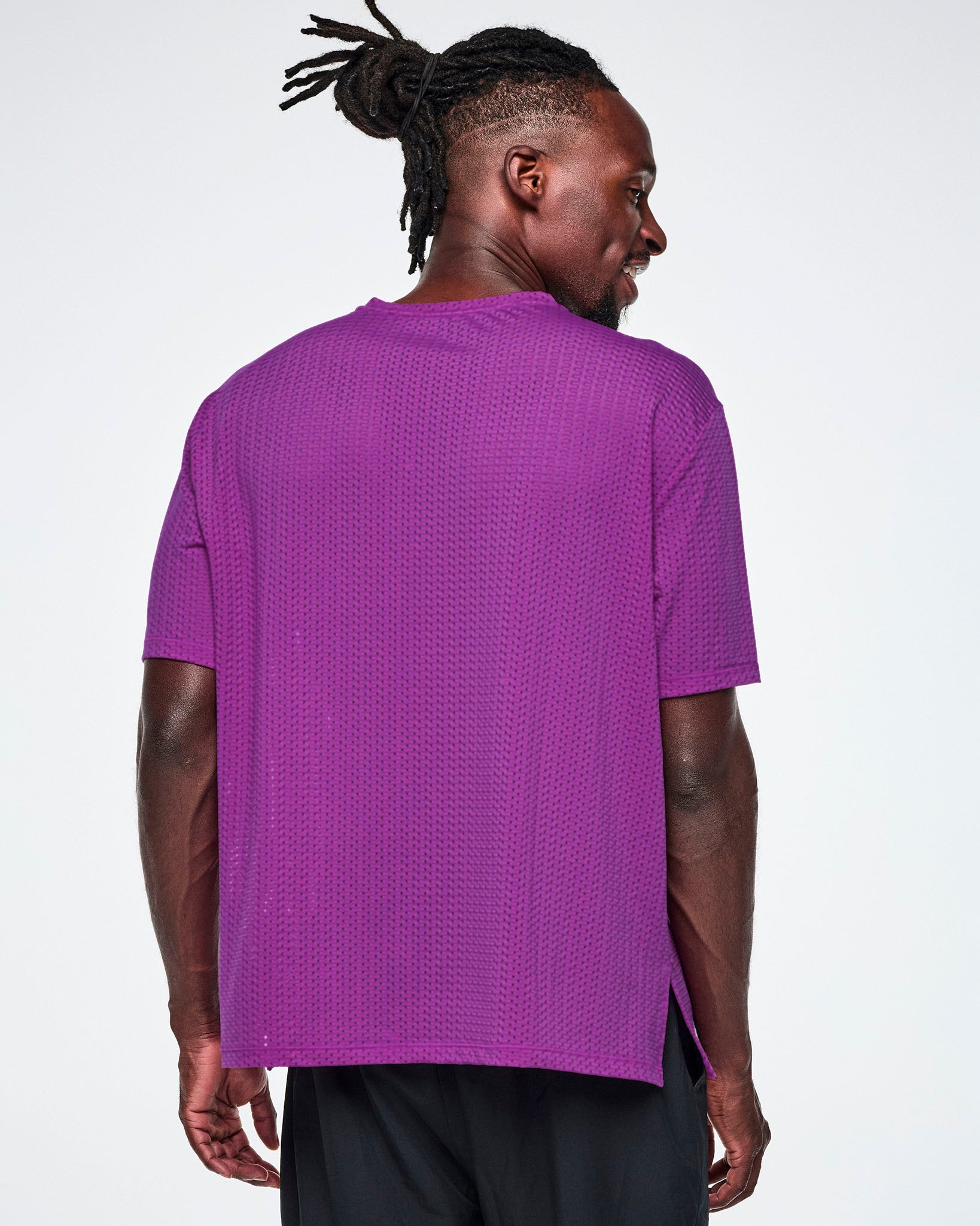 Back view of a male model in a purple oversized mesh boxy top, paired with black pants.