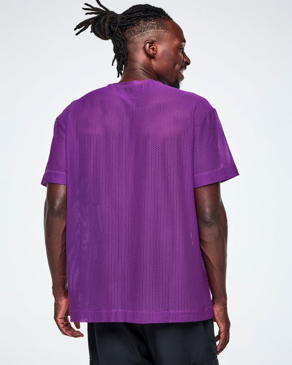 Back view of a male model wearing a purple Zumba mesh top, paired with black pants.