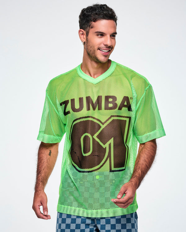 A male model wearing a green mesh Zumba tee with a large black “ZUMBA 01” on the front, paired with blue checkered denim pants.