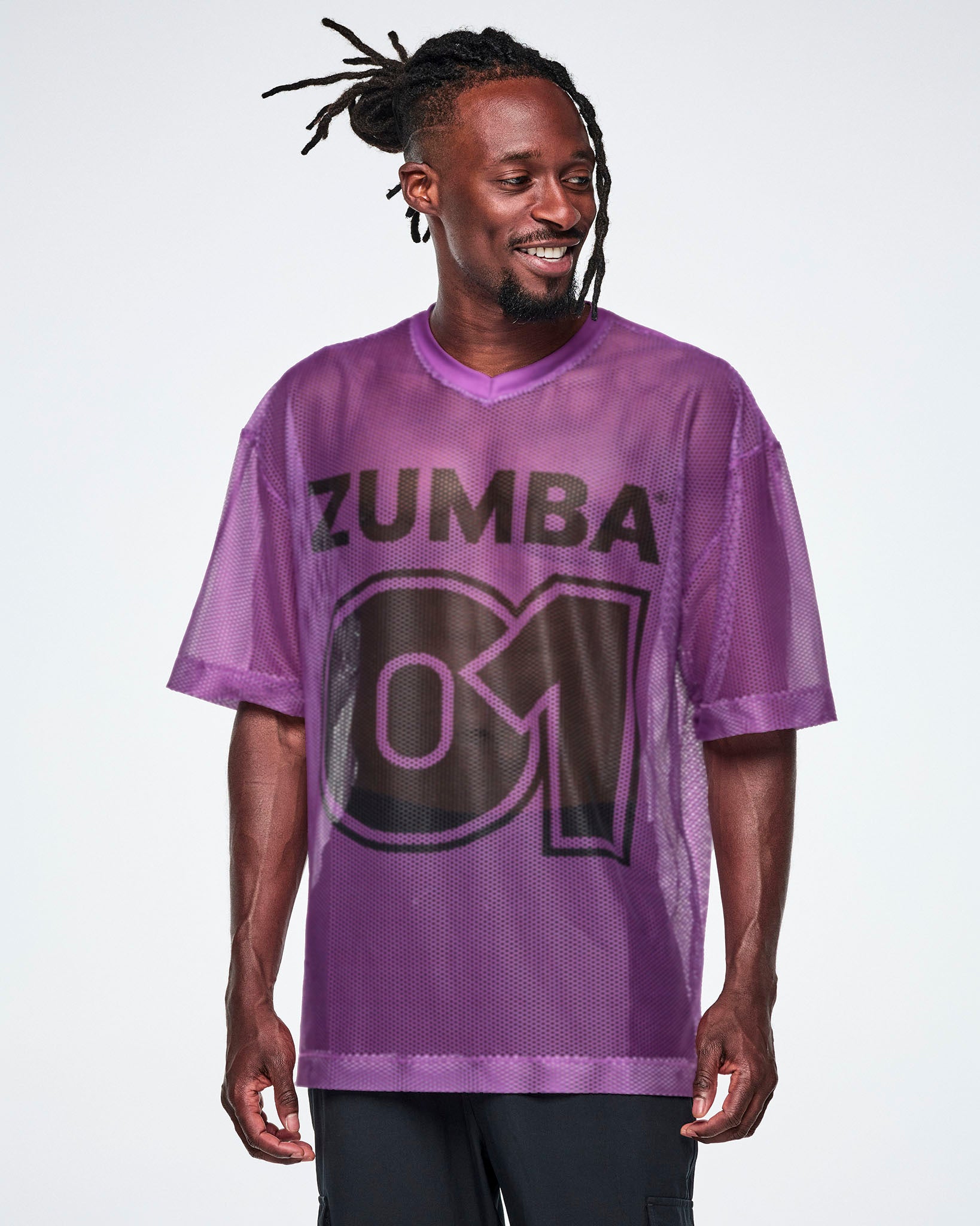 A male model wearing a purple mesh Zumba top with a large black "ZUMBA 01" printed on the front, paired with black pants.